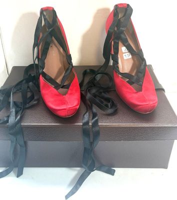 une paire de chaussures à talons hauts rouges et noires, posée sur une boîte noire
