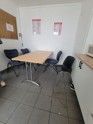 a woman sitting at a table in a room with chairs