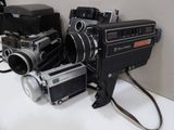 two old movie cameras sitting on a table next to each other