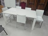 une table blanche avec quatre chaises et un meuble en arrière-plan