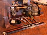 a wooden table topped with a tray filled with antique items