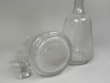 a glass bottle and a glass stopper on a white surface