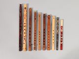 five wooden flutes lined up in a row on a white surface