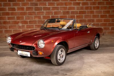 an image of a red sports car parked in front of a brick wall