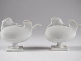 pair of white porcelain vases with birds on stands on a white surface