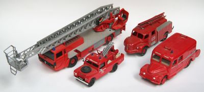 Plusieurs camions de pompiers miniatures sont alignés sur une surface blanche