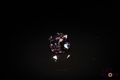 a close up of a purple diamond on a black surface