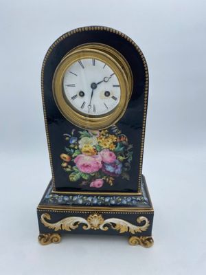 a black and gold clock with a floral design on it