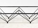 une table basse en métal noir et en verre posée sur un sol blanc