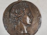 an old bronze medal with a woman ' s face on it