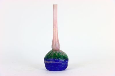 un vase bleu et vert posé sur une surface blanche
