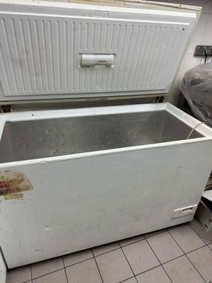 un vieux réfrigérateur blanc dans une cuisine au sol sale
