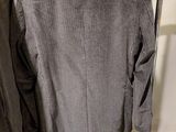two jackets hanging on a clothes rack in a room