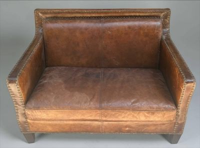 fauteuil en cuir marron avec des accoudoirs et des pieds cloutés