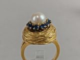a close up of a gold ring with a pearl and blue sapphires