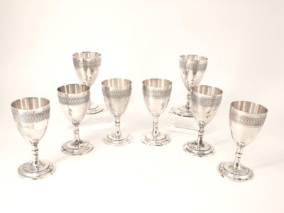 Plusieurs gobelets et tasses en argent sont alignés sur une surface blanche