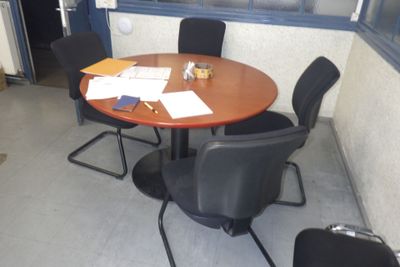 une table ronde avec quatre chaises et une valise posée dessus