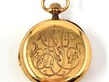 an image of a gold pocket watch with a monogram on it