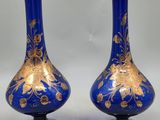 une paire de vases bleus ornés de motifs dorés sur fond blanc