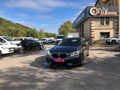 une BMW noire garée devant une concession BMW