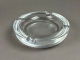 a glass ashtray on a table with a brown background