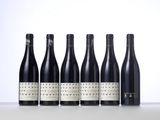 six bottles of wine lined up in a row on a table