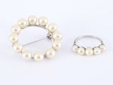 une paire de perles blanches et une bague en argent sur fond blanc