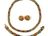 une photo d'un ensemble composé d'un collier et de boucles d'oreilles posé sur un fond blanc