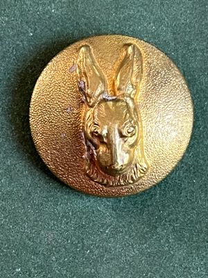 une image représentant une tête de chien sur un bouton en or