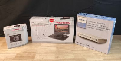 trois boîtes posées sur une table où se trouve un appareil photo