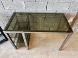 une table en verre avec une base en métal et un plateau en verre