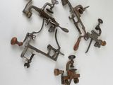 un ensemble de quatre anciennes pinces en métal et en bois posées sur une surface blanche