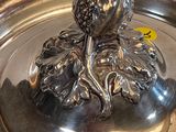 a silver plate with a silver figurine sitting on top of it