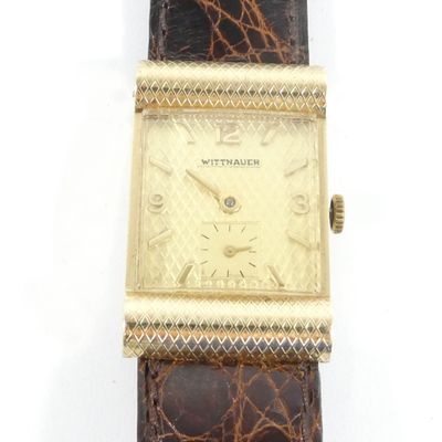 une photo d'une montre en or avec un bracelet en cuir d'alligator marron