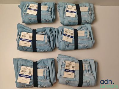 six paires de jeans bleus sont empilées sur une table