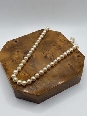un gros plan d'une boîte en bois sur laquelle est posé un collier de perles