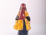 yellow and black ceramic figurine of a woman with a red hat