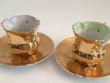 two cups and saucers that are sitting on a table
