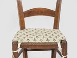 an old wooden chair with a floral seat pad on a white background