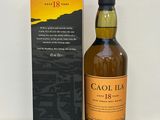 une photo montrant une bouteille de whisky posée à côté d'une boîte sur une table