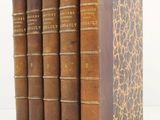three old books sitting on top of each other on a white surface