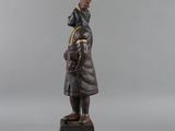 a statue of a man in a coat and hat on a pedestal