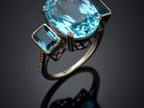 a blue topaze and diamond ring on a black surface