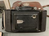 a black camera sitting on a table next to a brown case