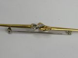 a close up of a gold tie bar on a white surface