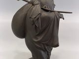 statue of a man carrying a bag with a stick on his back