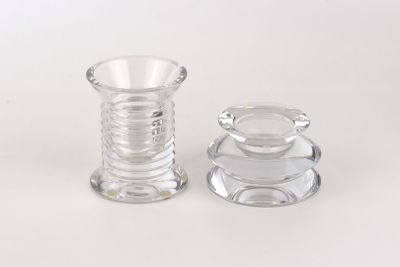 deux bougeoirs en verre transparent posés sur une surface blanche