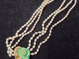 un long collier de perles orné d'une fleur verte et d'un pompon