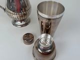 a silver shaker and a silver cup on a table