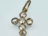 a close up of a gold cross pendant on a white surface